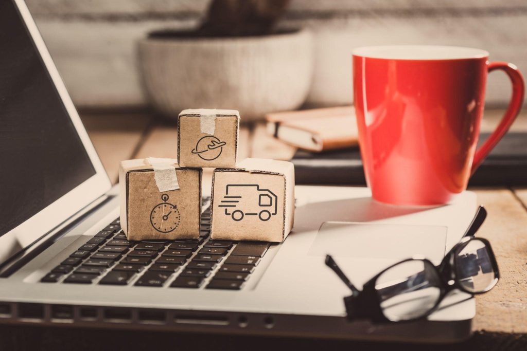 Mini shipping boxes on laptop beside coffee—local digital marketing services optimizing online booking for movers and storage